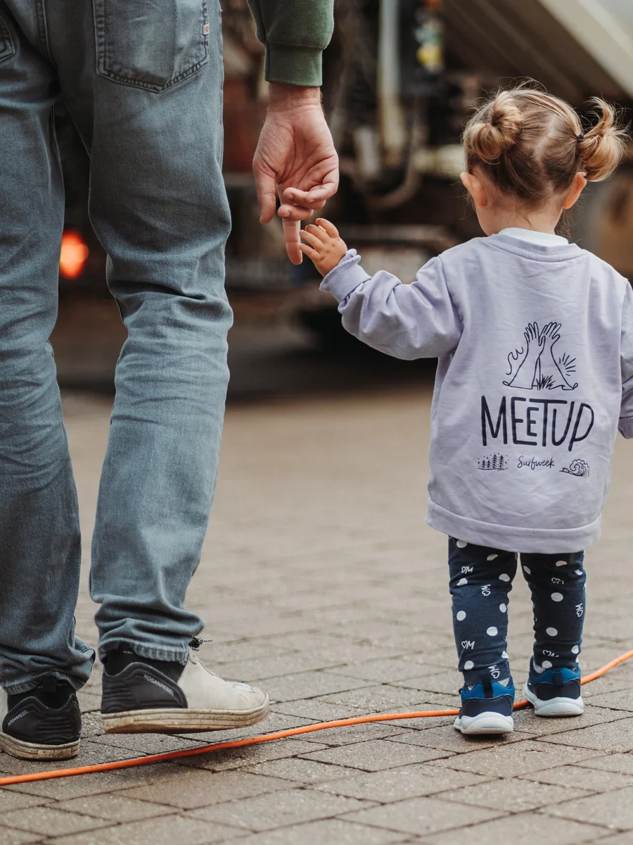 Una bambina con la felpa del MeetUp cammina tenendo la mano di un adulto
